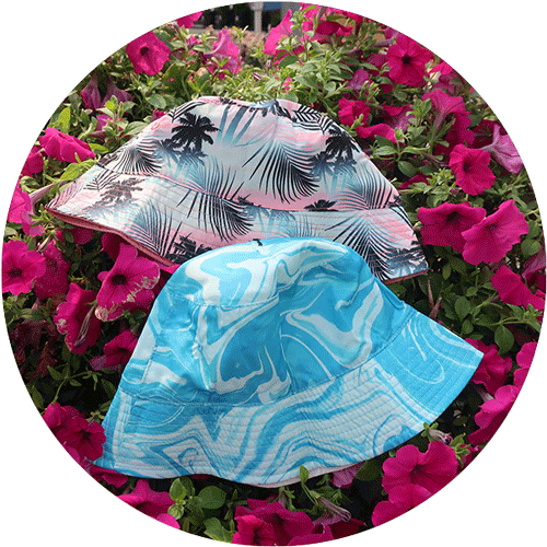 A blue marbled kids bucket hat and a pink and blue palm tree bucket hat.